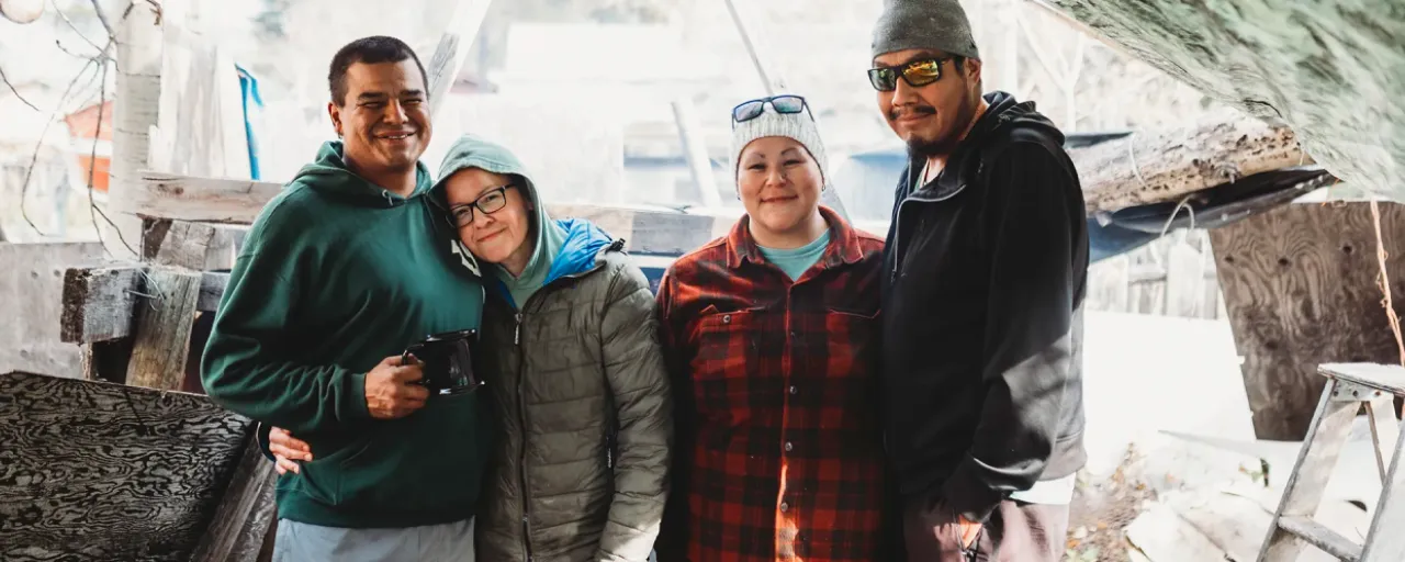 A group of four smiling people standing together outside